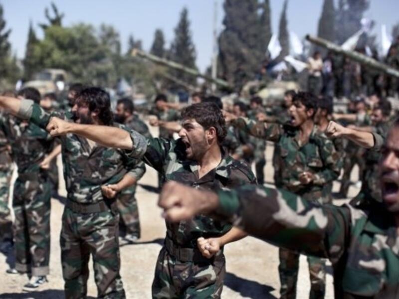 Members of rebel brigades parade at a former military academy north of Aleppo. Syrian rebels have expressed disdain for US President Barack Obama after he backed away from striking over alleged chemical weapons attacks, while saying the world doesn't really care about Syria. (AFP)