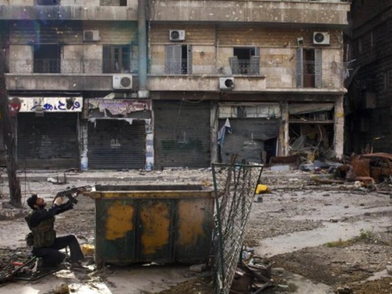 A Syrian rebel aims his weapon as he takes position behind a makeshift barricade during clashes with regime forces in the Salaheddine district of Aleppo in northern Syria on Saturday. (Photo: AFP / JM LOPEZ)