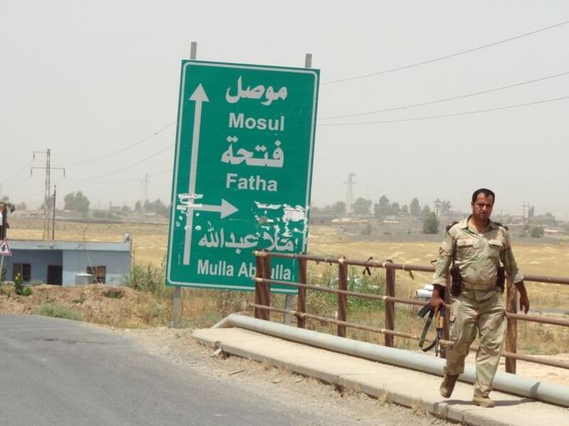 An Iraqi solider walks past a sign pointing toward Mosul. (AFP/File)