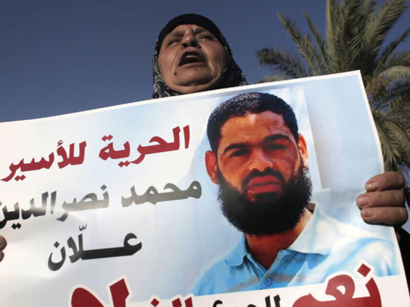 The mother of Muhammad Allan holds a sign calling for his release. (AFP/File)