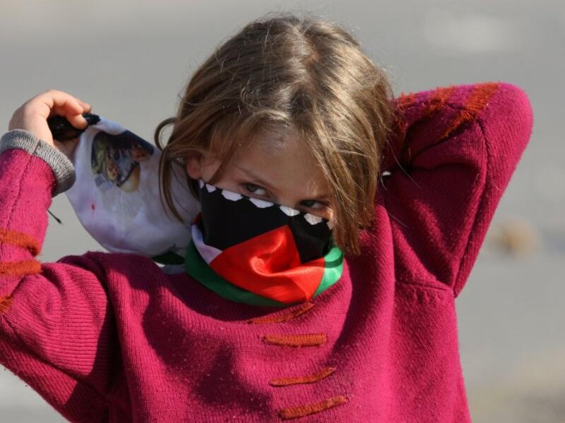 A Palestinian girl wraps a scarf around her face to protect from tear gas. (AFP/File)