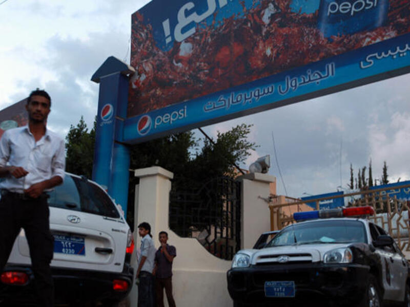 Yemeni policemen and people gather at the scene where the bodyguard of Germany's ambassador to Yemen was killed in the southern Sanaa district of Hada. (Image credit: AFP)