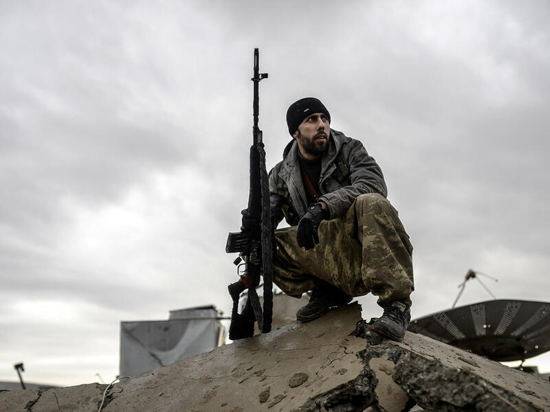 A member of the YPG, the military wing of the Kurdish PYD party, sits on rubble in Syria. (AFP/File)