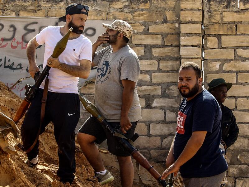 Libyan fighters loyal to the Government of National Accord (GNA) hold rocket-propelled grenade (RPG) launchers as they stand behind a dirt barrier during clashes with forces loyal to strongman Khalifa Haftar south of the capital Tripoli's suburb of Ain Zara, on April 10, 2019. Mahmud TURKIA / AFP