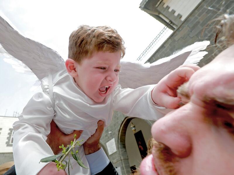 A toddler in angel costume pinches a man as Catholic believers gather outside Greek-Melkite Patriarchal Cathedral of the Dormition of Our Lady to mark Palm Sunday in the capital Damascus in Bab Sharki, Old Damascus on April 14, 2019.  LOUAI BESHARA / AFP
