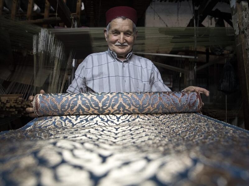 Abdelkader Ouazzani, the last of Morocco's brocade master weavers, displays tapestry at his workshop in the old city of Fez on April 10, 2019. His skilfull hands intricately create shimmering silk fabrics, enhanced with gold or silver thread, for bridal jewellery, designer creations or high-end furnishings. FADEL SENNA / AFP