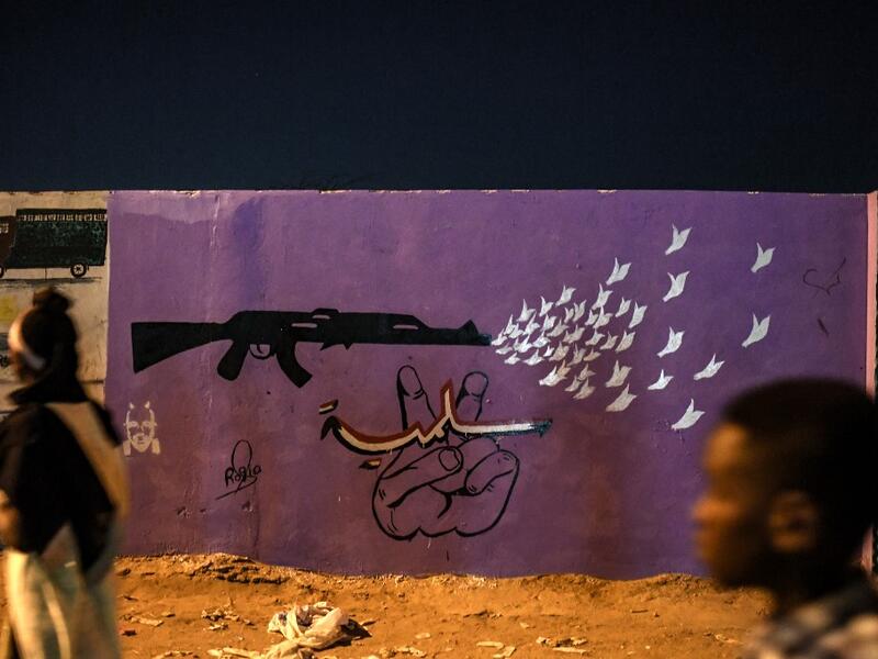 Sudanese protestors walk in front of a recently painted mural during a protest outside the army complex in the capital Khartoum. OZAN KOSE / AFP