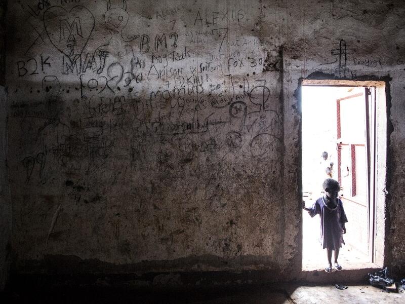 A young South Sudanese Refugee stands on the doorstep of a building located in a transition camp for South Sudanese refugees who have just arrived in Aru. JOHN WESSELS / AFP