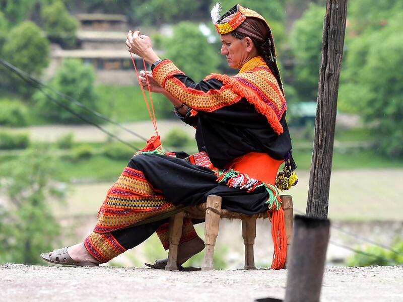 In this picture a Kalash woman wearing a traditional dress knits clothes outside her house after celebrating 'Joshi', a festival to welcome the arrival of spring, at Bumburate village in the mountainous valleys in northern Pakistan. AAMIR QURESHI / AFP