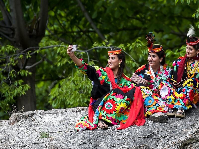 In a remote valley in Pakistan dozens of Kalash minority women dance to celebrate spring's arrival -- but as a gaggle of men scramble to catch them on camera, the community warns an influx of domestic tourists is threatening their unique traditions.  AAMIR QURESHI / AFP
