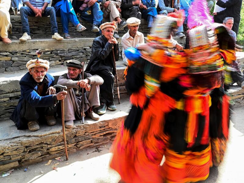 In this picture  Kalash elderly men watch women dancing as they celebrate 'Joshi', a festival to welcome the arrival of spring, at Bumburate village in the mountainous valleys in northern Pakistan.  AAMIR QURESHI / AFP