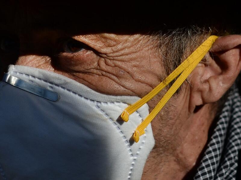 A pilgrim wearing a mask awaits the effigy of the Rocio Virgin during a procession at the village of El Rocio  CRISTINA QUICLER / AFP