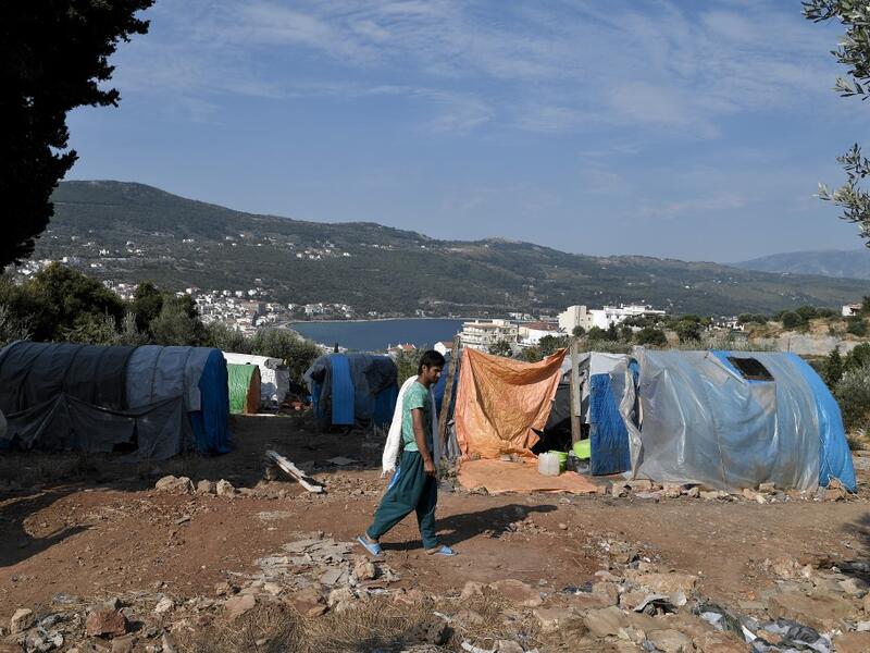 A migrant walks to take a shower at the makeshift refugee camp above the city of Vathy on the island of Samos early. LOUISA GOULIAMAKI / AFP