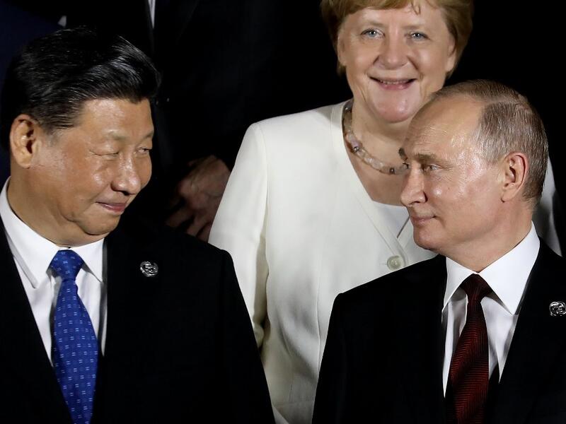 German Chancellor Angela Merkel stands behind Russian President Vladimir Putin (front R) and Chinese President Xi Jinping as they arrive to pose for a group photo before a cultural event at the Osaka Geihinkan in Osaka Castle Park during the G20 Summit in Osaka on June 28, 2019.  Dominique JACOVIDES / POOL / AFP