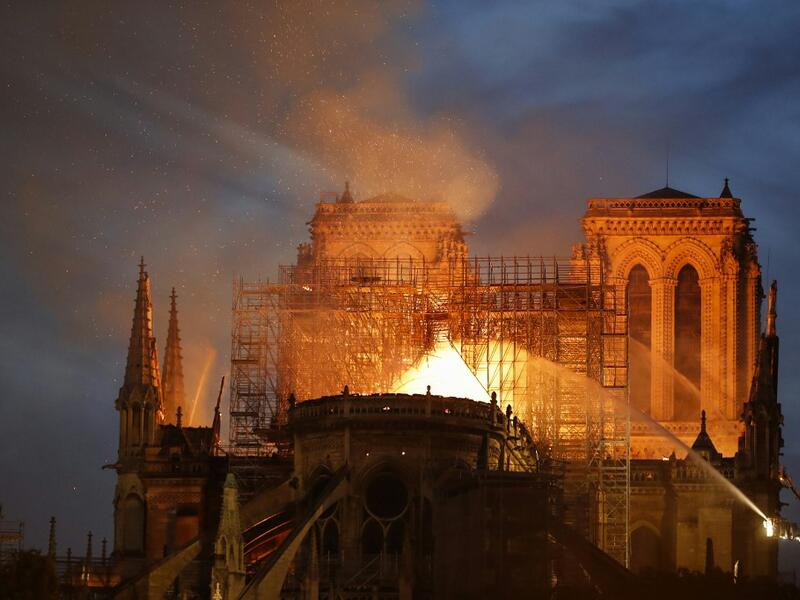 A Firefighter douse flames billowing from the roof at Notre-Dame Cathedral in Paris on April 15, 2019. A major fire broke out at the landmark Notre-Dame Cathedral in central Paris sending flames and huge clouds of grey smoke billowing into the sky. FRANCOIS GUILLOT / AFP