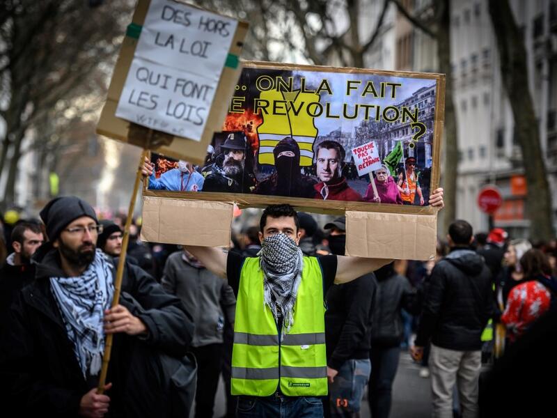 A man wearing a yellow vest (gilet jaune) holds a placard reading "we are going to do the revolution" as he takes part in a demonstration in Lyon on December 17, 2019 to protest against French government's plan to overhaul the country's retirement system, as part of a national general strike. (AFP/ File Photo)