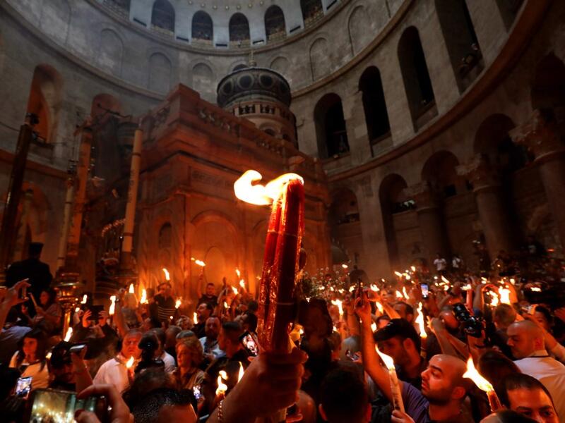 Christian Orthodox worshippers hold up candles lit from the ‘Holy Fire’ as they gather in the Church of the Holy Sepulchre in Jerusalem’s Old City on April 27, 2019. GALI TIBBON / AFP