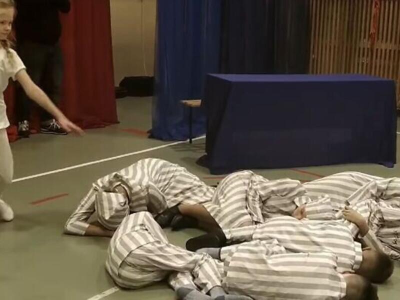 A schoolgirl dances around classmates dressed as concentration camp inmates who were gassed to death during an Auschwitz-themed event in Łabunie, Poland on December 10. (Screenshot)