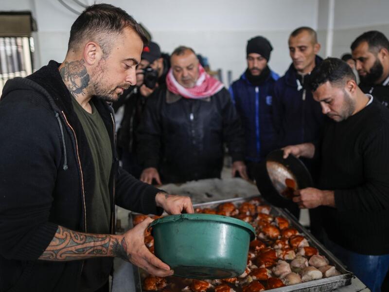 Gabriele Rubini (L), known as Chef Rubio, cooks with Palestinian prisoners at a Hamas-run civilian prison in Gaza City on January 21, 2020, where he is teaching the inmates how to cook Italian food and they teach him Palestinian recipes. MAHMUD HAMS / AFP