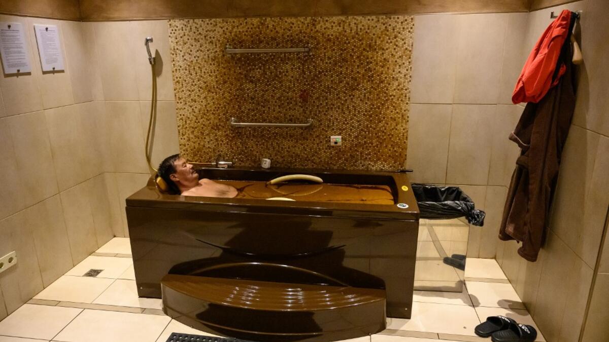 A man bathes in a tub filled with Naftalan crude oil during a treatment session at Qarabag luxury resort in Naftalan, some 300 kilometres (186 miles) from capital Baku, on March 21, 2019. Immersed up to her neck in crude oil, a Russian woman suffering from joint disease smiles in delight, confident that the treatment at a spa in northwestern Azerbaijan will cure her painful condition.  Mladen ANTONOV / AFP