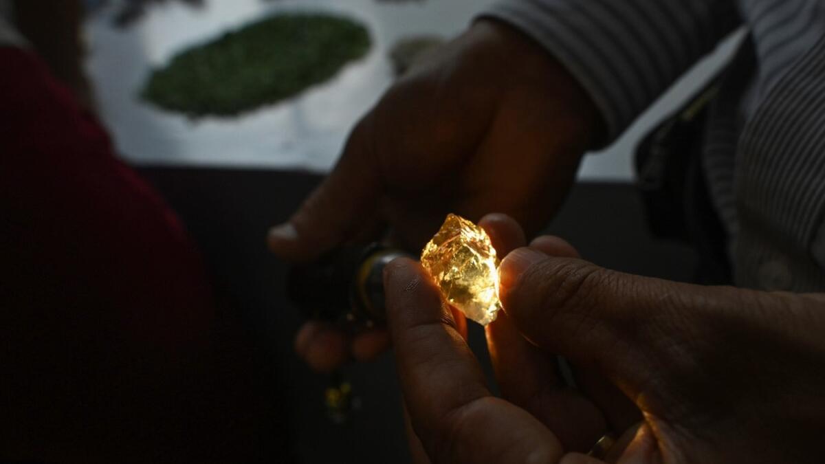 This photo taken on May 17, 2019 shows a buyer inspecting a gemstone at the gems market in Mogok town, north of Mandalay. Burrowing deep underground, thousands of informal miners risk their lives to find gleaming red gems as a law change spurs opportunity in Myanmar's "land of rubies". Ye Aung THU / AFP
