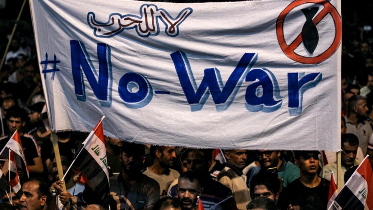 Iraqi followers of Shiite Muslim cleric Moqtada al-Sadr wave national flags and raise protest signs as they demonstrate in the capital Baghdad's central Tahrir Square late on May 24, 2019, against involvement in any conflict between Iran and the United States.  AHMAD AL-RUBAYE / AFP