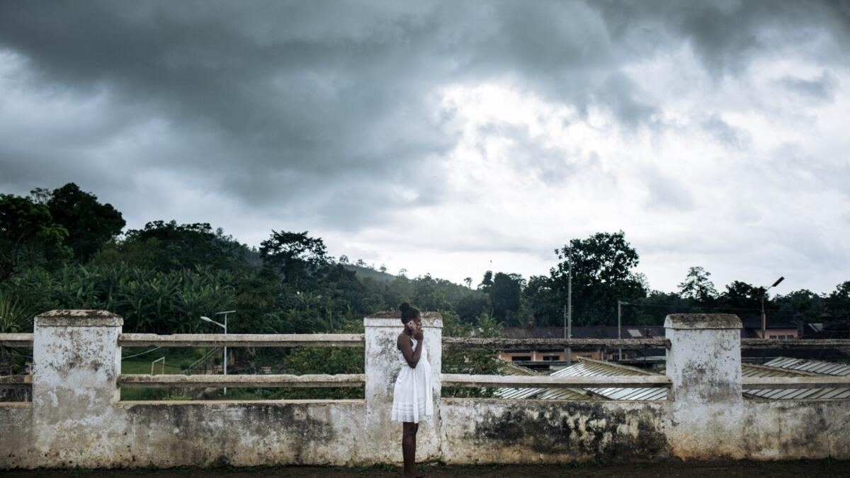 An inhabitant of the roca Agostinho Neto, an abandoned cocoa plantation of Sao Tome and Principe, phones on the paved road of the roca, on May 29, 2019.  Alexis HUGUET / AFP