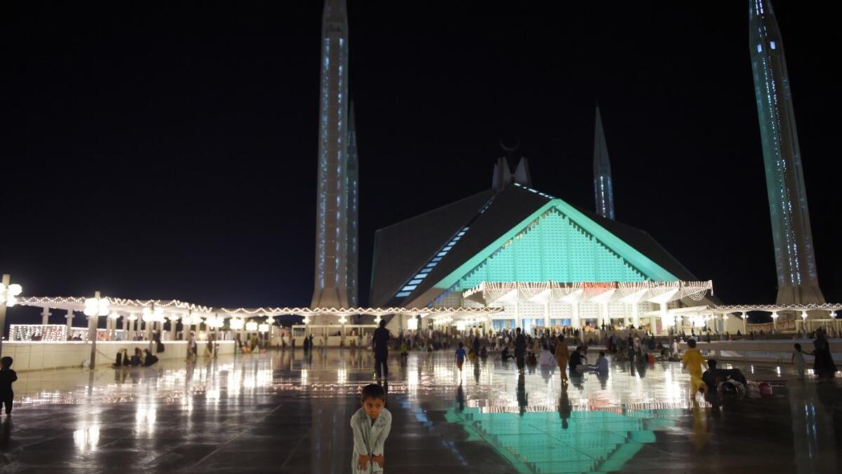 A child joins Pakistani Muslim worshippers and they gather at the illuminated Grand Faisal Mosque on the 27th night of the Holy month of Ramadan, in Islamabad on June 1, 2019.  The 27th night is known as Lailat al-Qader. FAROOQ NAEEM / AFP