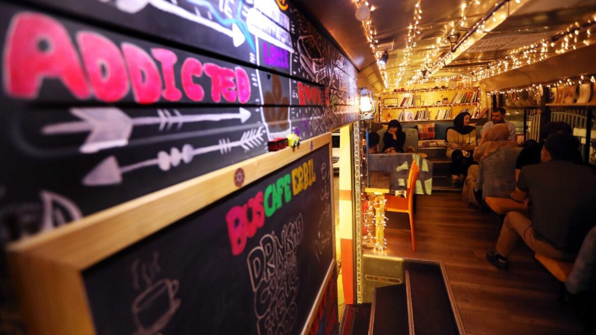 People have a drink at "The Bus Cafe Erbil" in Arbil, the capital of Iraq's Kurdish autonomous region, on June 7, 2019, on the long weekend of the Eid al-Fitr holiday which marks the end of the Muslim holy month of Ramadan.  SAFIN HAMED / AFP