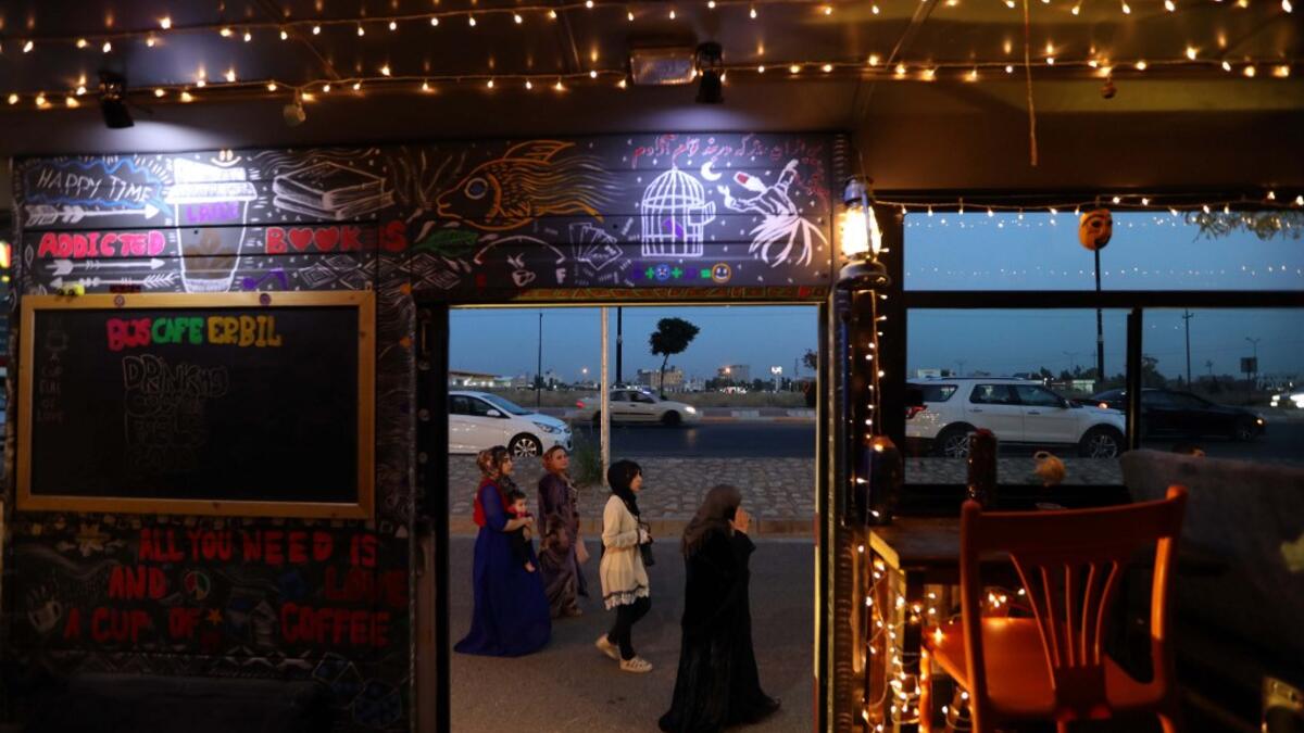Muslim women walk past "The Bus Cafe Erbil" in Arbil, the capital of Iraq's Kurdish autonomous region late on June 7, 2019, on the long weekend of the Eid al-Fitr holiday which marks the end of the holy fasting month of Ramadan.  SAFIN HAMED / AFP