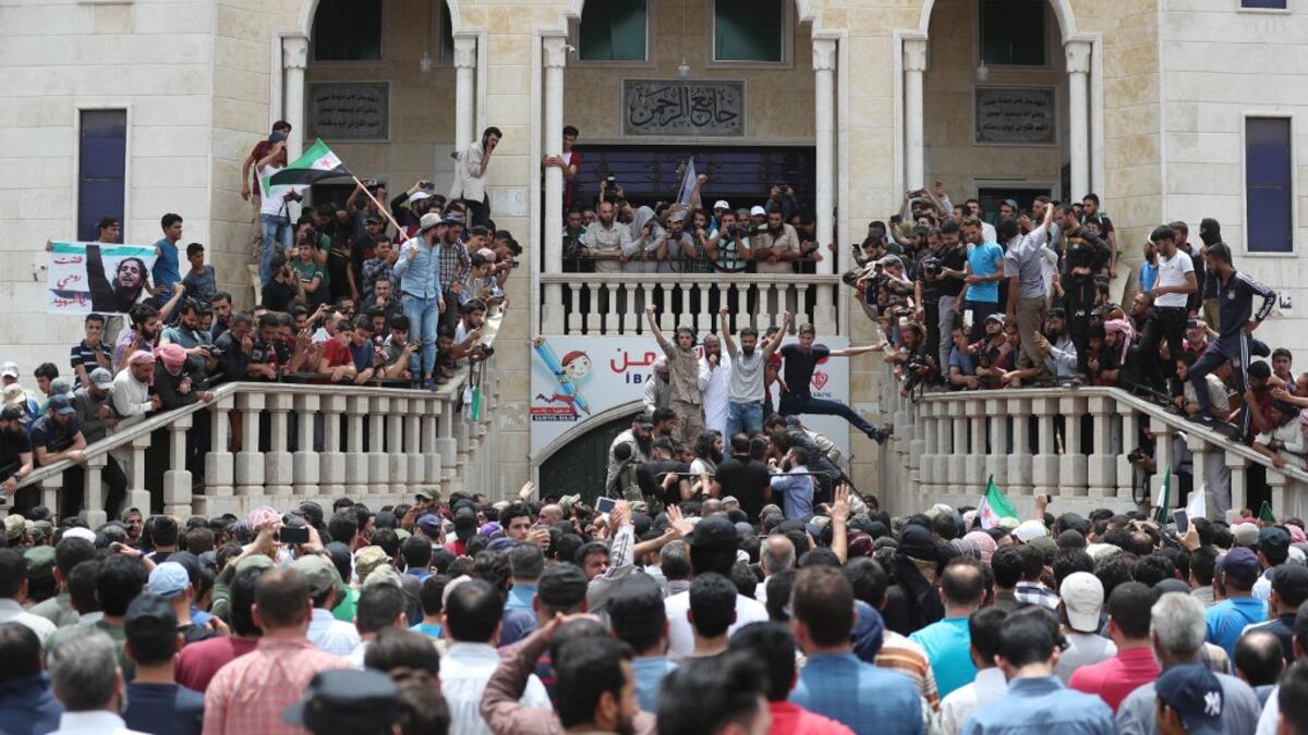 A picture taken on June 9, 2019 shows Syrians waving rebel flags and portraits of Abdel-Basset al-Sarout during the funeral of the late rebel fighter in al-Dana in Syria's jihadist-controlled Idlib region, near the border with Turkey. OMAR HAJ KADOUR / AFP