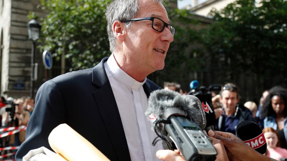 A member of the church answers journalists questions prior to entering the Notre-Dame de Paris cathedral, to take part in a mass, the first since the fire that destroyed the cathedral's roof on April 15, in Paris on June 15, 2019. Zakaria ABDELKAFI / AFP