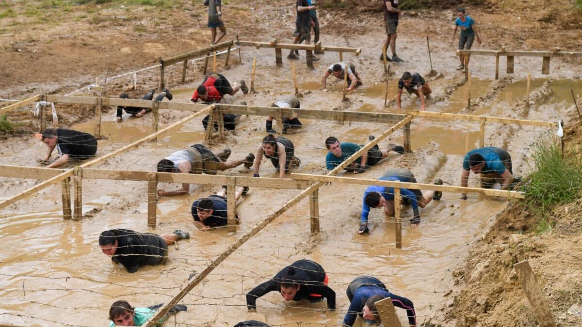 Runners crawl in the mud under barbed wire as they take part in the Mud Day, a 13km race with obstacles in Beynes, near Paris on June 16, 2019.  ALAIN JOCARD / AFP