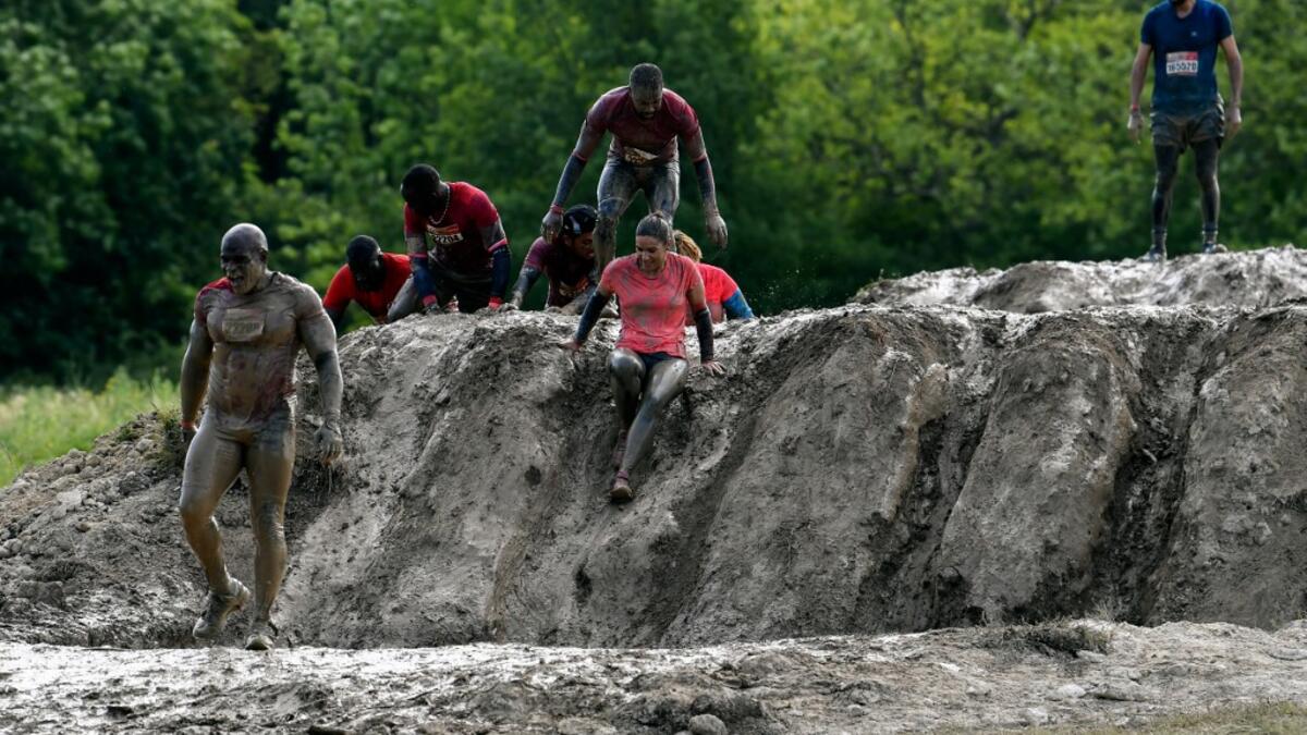 Runners cross an obstacle as they take part in the Mud Day, a 13km race with obstacles in Beynes, near Paris on June 16, 2019.  ALAIN JOCARD / AFP