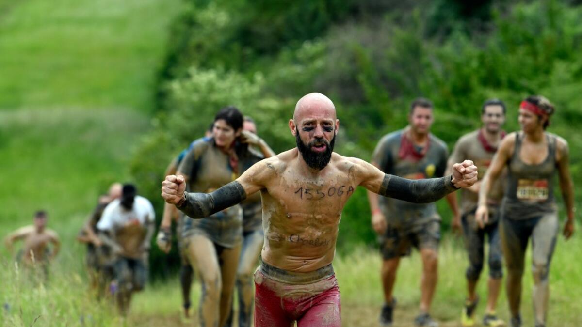 A runner gestures as he takes part in the Mud Day, a 13km race with obstacles in Beynes, near Paris on June 16, 2019.  ALAIN JOCARD / AFP