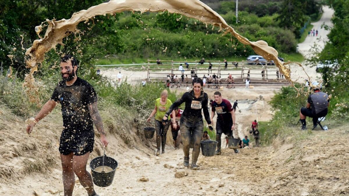 Mud is thrown at runners as they take part in the Mud Day, a 13km race with obstacles in Beynes, near Paris on June 16, 2019.  ALAIN JOCARD / AFP