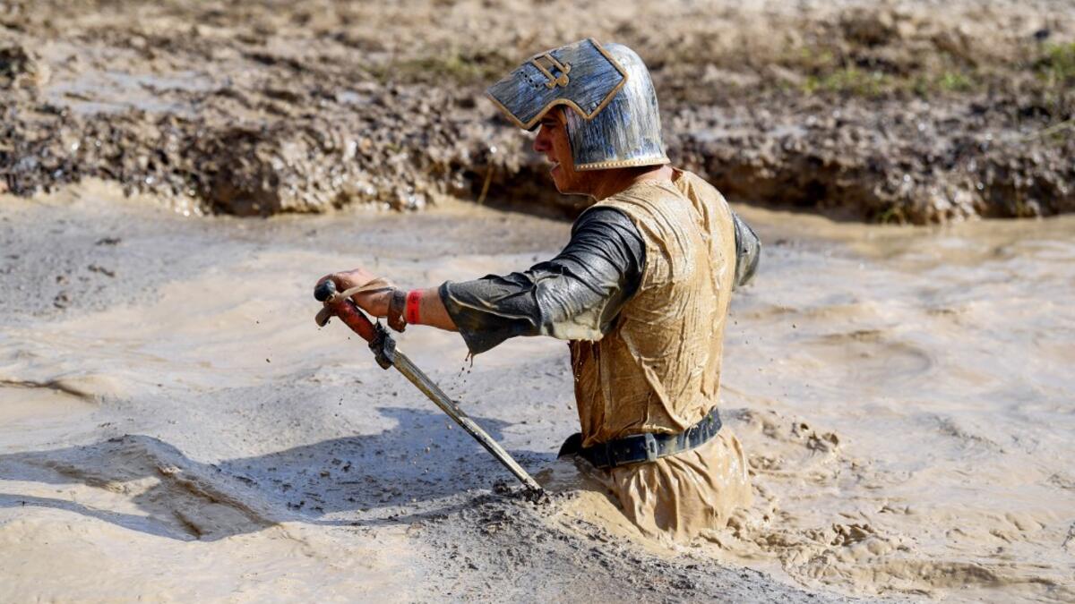 A runner wearing a medieval knight costume takes part in the Mud Day, a 13km race with obstacles in Beynes, near Paris on June 16, 2019.  ALAIN JOCARD / AFP