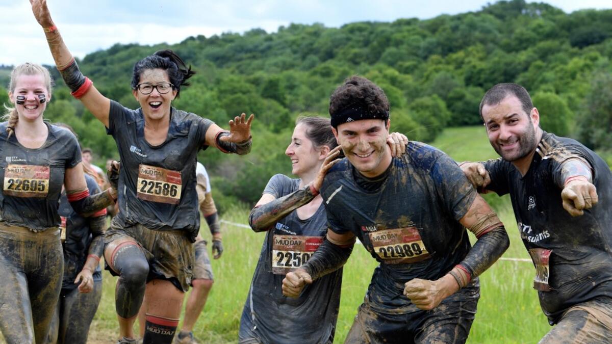 Runners cheer as they take part in the Mud Day, a 13km race with obstacles in Beynes, near Paris on June 16, 2019.  ALAIN JOCARD / AFP
