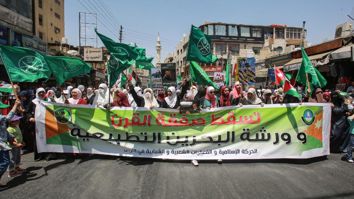 Women march with flags of the Muslim Brotherhood behind a large banner  reading in Arabic "down with the deal of the century and the normalisation  workshop of Bahrain", during a post-Friday prayers demonstration in the  Jordanian capital Amman on June 21, 2019, against US President Donald Trump's "Deal of the Century".  Khalil MAZRAAWI / AFP