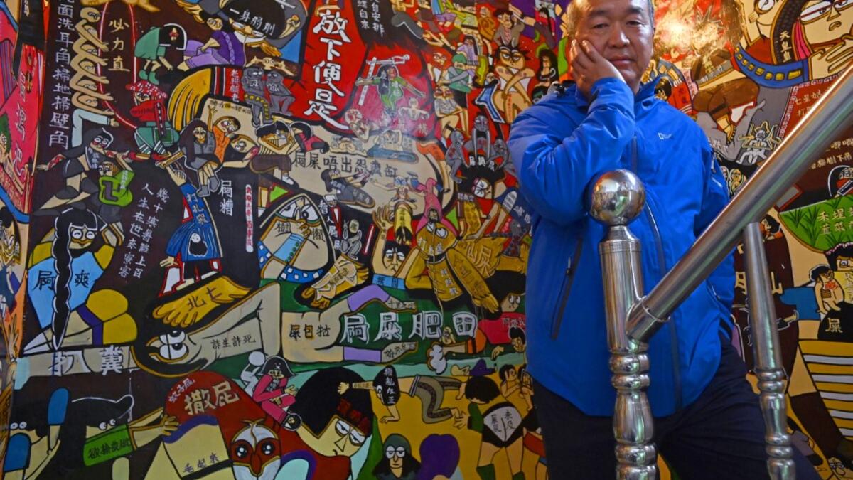 This picture taken on March 30, 2019 shows Hakka graffiti artist Wu Tsun-hsien posing for photos at his home in the Taiwanese village of Ruan Chiao. Nestled in the mist-covered foothills of Taiwan's central mountain range, Ruan Chiao village is virtually devoid of young people, but artist Wu Tsun-hsien is coaxing the Instagram generation back by transforming local homes into a canvas of colour. Sam YEH / AFP