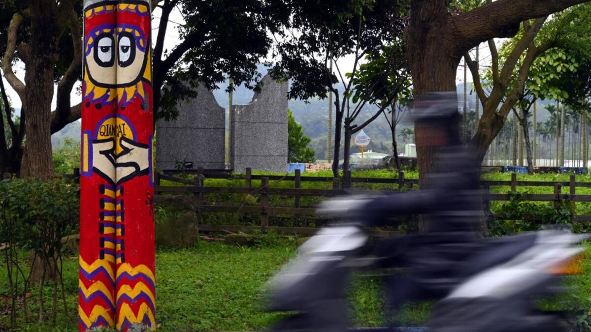 This picture taken on March 30, 2019 shows an motorcyclist riding past a utility pole painted by Hakka graffiti artist Wu Tsun-hsien in the Taiwanese village of Ruan Chiao. Nestled in the mist-covered foothills of Taiwan's central mountain range, Ruan Chiao village is virtually devoid of young people, but artist Wu Tsun-hsien is coaxing the Instagram generation back by transforming local homes into a canvas of colour. Sam YEH / AFP