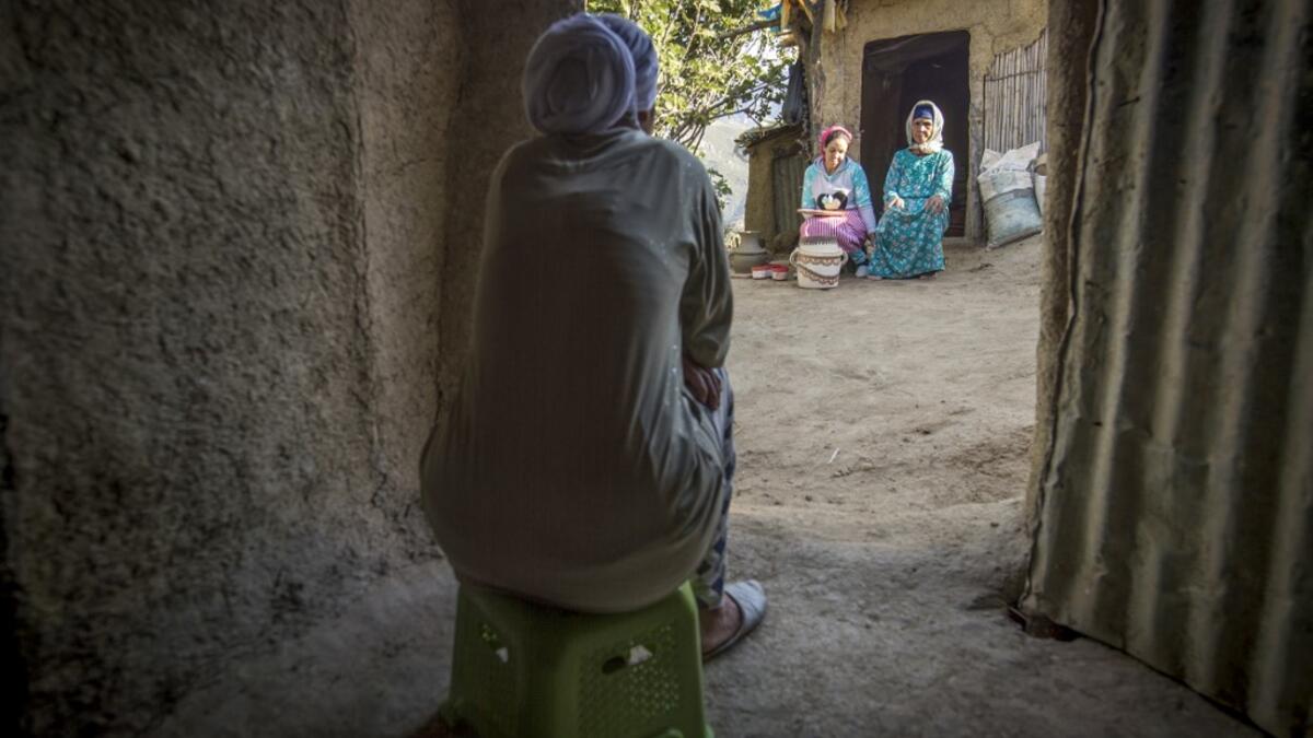 A neighbour watches as Moroccan potter Houda Oumal (C) sitting next to her mother Fatima Harama (R) paints with natural pigments on one of her pieces of pottery, near the village of Ourtzagh in the region of Taounate on june 11, 2019. FADEL SENNA / AFP