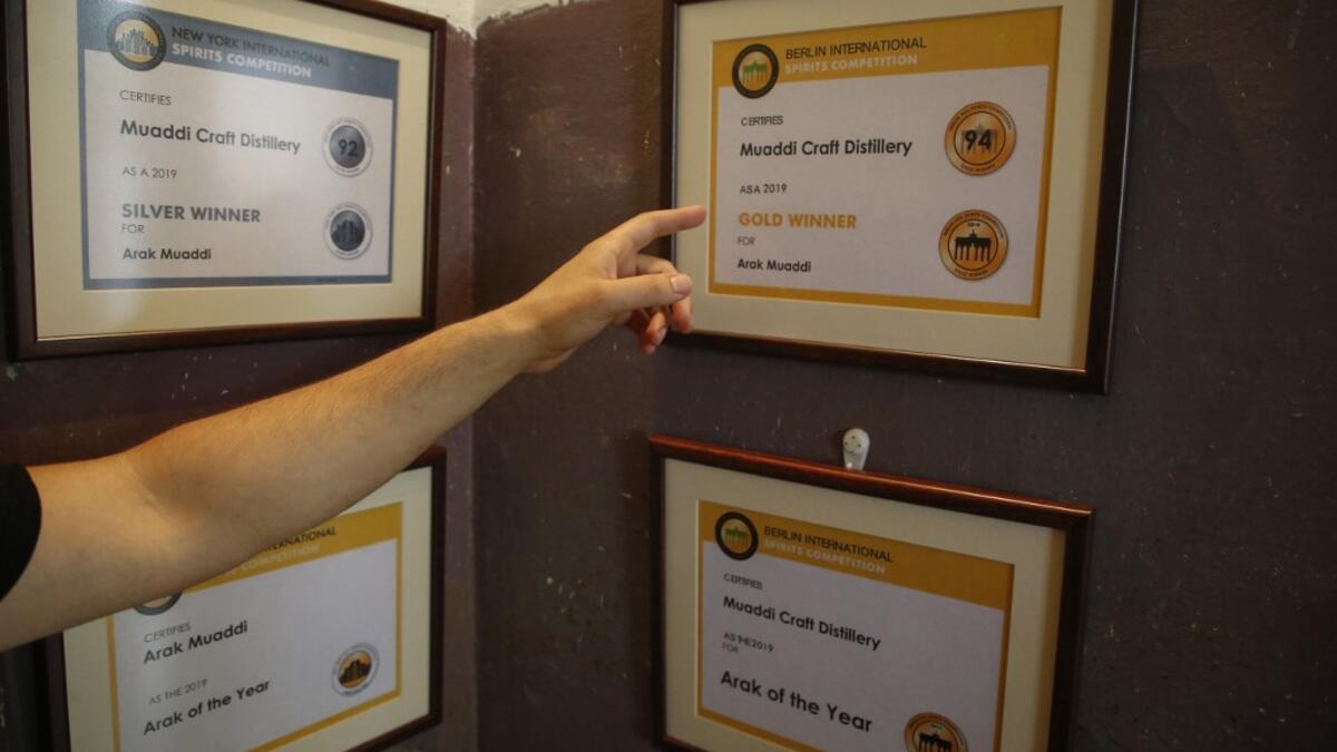 Palestinian distiller Nader Muaddi points at the awards he won in the West Bank village of Beit Jala, near Bethlehem, on June 16, 2019. In his basement, distiller Muaddi made fewer than 500 bottles of liquor last year, but it is earning global acclaim and reviving interest in the Palestinian alcohol sector. On the outskirts of the city famed for Jesus's birth, the 35-year-old illustrates the handcrafted way he makes Arak, an anise-flavoured drink popular in the Middle East and similar to Greek Ouzo, French