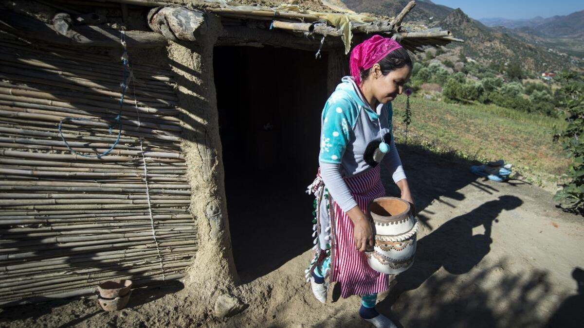 Moroccan potter Houda Oumal from the M'tioua tribe carries one of her pottery works near the village of Ourtzagh in the region of Taounate on june 11, 2019. FADEL SENNA / AFP