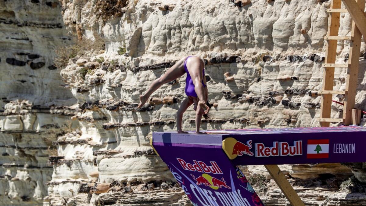 A cliff diver prepares to jump from a platform on the landmark Raouche sea rock off the coast of the Lebanese capital Beirut on July 14, 2019, during the women's 2019 Red Bull Cliff Diving World Series.  ANWAR AMRO / AA / AFP
