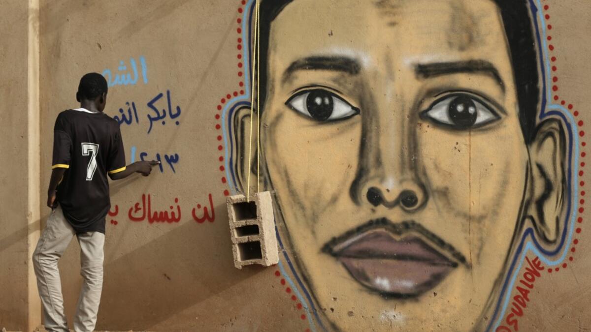 A man walks past the mural painting of Babikir Anwar on the wall of the family home in the neighbourhood of Shambat, in the Sudanese capital Khartoum.  ASHRAF SHAZLY / AFP