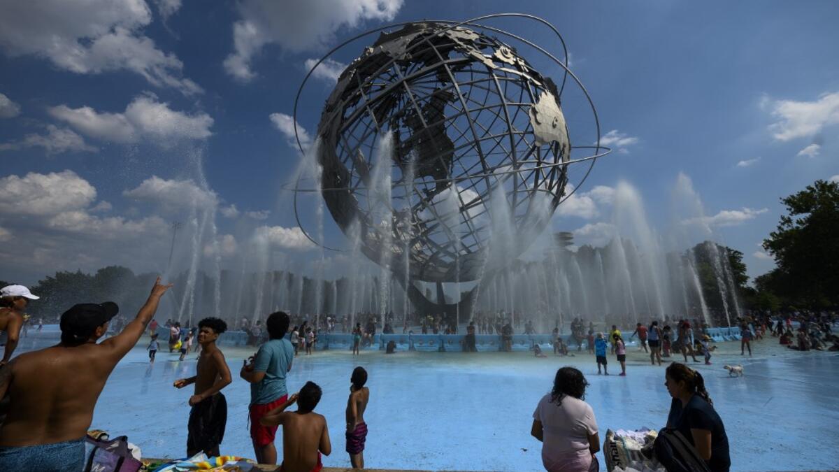 People enjoy refreshing water of a fountain in the Unisphere fountain at Flushing Meadow Corona Park in the borough of Queens on July 21, 2019 in New York City. Johannes EISELE / AFP