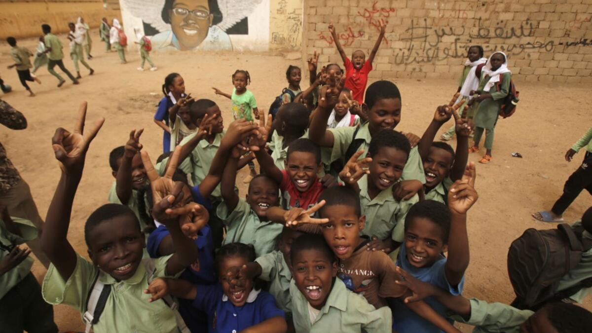 Pupils gesture in front of a mural painting of a protester killed during anti-government protests in the Sudanese capital Khartoum. ASHRAF SHAZLY / AFP