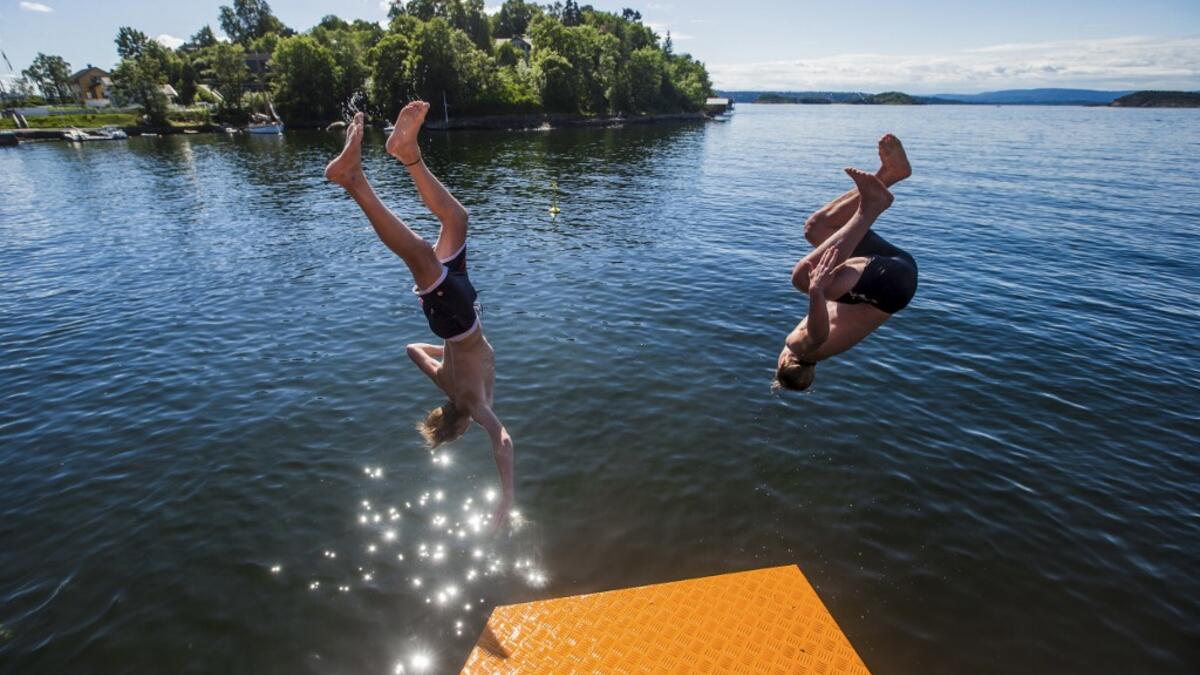 People plunge into the water of the newly opened Bekkelagsbadet in Oslo, between Mosseveien and the bridge over Ormoya, on July 23, 2019, as a new heatwave hits Europe.  Trond Reidar Teigen / NTB scanpix / AFP