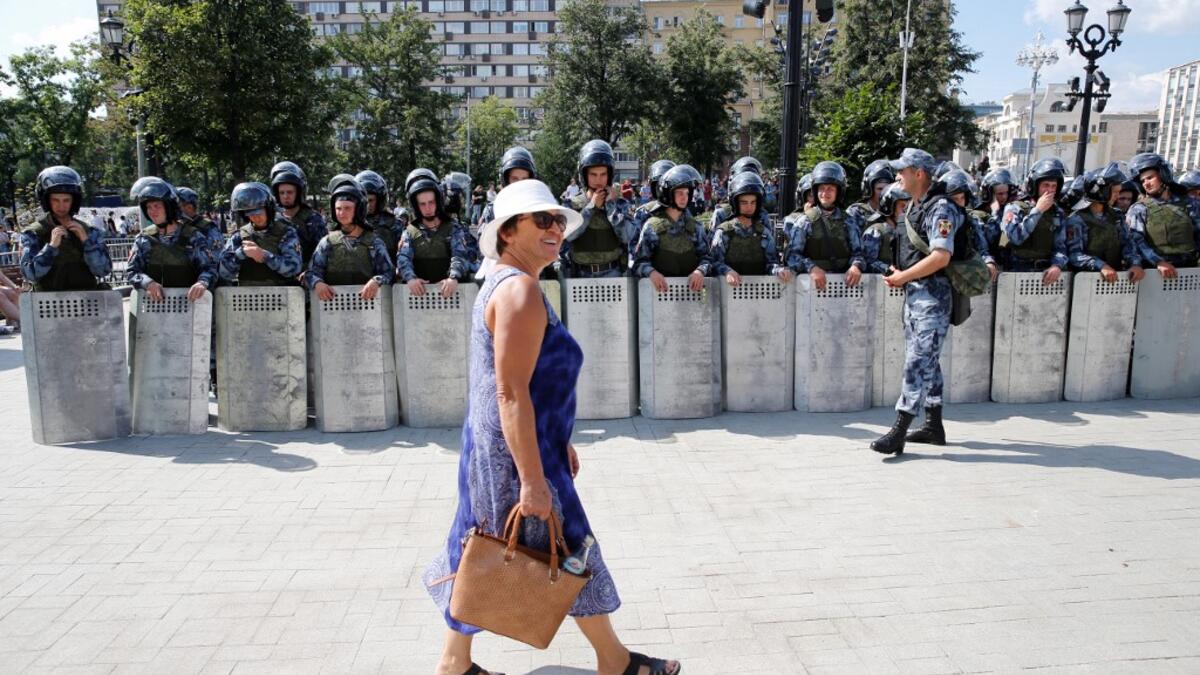 A woman walks past servicemen of the Russian National Guard during an unauthorised rally demanding independent and opposition candidates be allowed to run for office in local election in September, in downtown Moscow on July 27, 2019.  Maxim ZMEYEV / AFP
